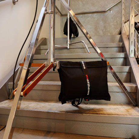 Portable RoadBags black sandbag securely stabilizing equipment on set stairs for professional use.